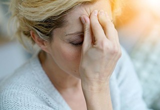 Woman holding her forehead, struggling with TMD headache