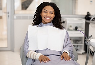 Female dental patient sitting in chair and smiling