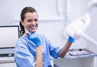 Young woman in orange dental chair holding Invisalign tray