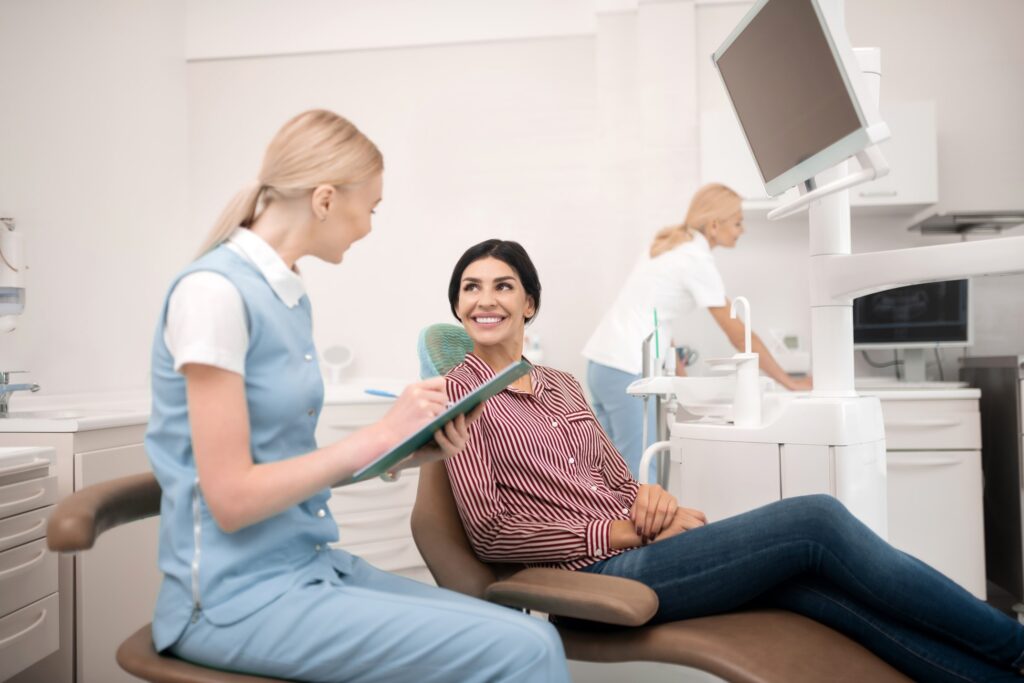 Smiling patient talking to dental assistant in office